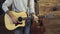 Close up mans hands tuning an acoustic guitar slow motion