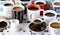 Close up of many cups of coffee in various mugs and cups.