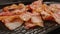 CLOSE UP: Many strips af bacon on a black pan