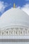 Close-up marble domes with golden pillar with Islamic sign on the top of Sheikh Zayed Grand Mosque with blue sky in the morning