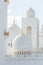 Close-up marble domes with golden pillar with Islamic sign on the top of Sheikh Zayed Grand Mosque with blue sky in the morning