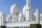 Close-up marble domes with golden pillar with Islamic sign on the top of Sheikh Zayed Grand Mosque with clouded sky in the morning