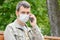 Close-up of a masked man with a phone on the street, looked into the frame