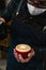 Close-up of a masked unrecognizable barista making a cappuccino