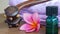 Close up of massage tools, massage oil and pink frangipani flowers on a wooden table