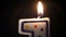 A close-up match lights a festive candle in the form of a number one, beautiful reflections around the fire. Then the