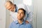 Close-up of mature adult male doctor chiropractor osteopath talking with young man patient sitting in chair, asks about