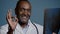 Close-up mature african american man doctor surgeon traumatologist radiologist in medical coat in studio blue background