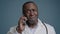 Close-up mature african american man talking mobile phone in studio gray background confused puzzled doubting male