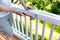 Close up of mature man hammering nail into white railing of outdoor deck