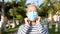 Close up of mature senior woman happy putting on her face medial and surgical mask - stay safe wearing mask and stay at home - smi