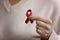 Close up mature senior woman holding red awareness ribbon