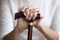 Close up mature woman holding hands on walking stick, cane