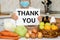 Close up mature woman in protective mask sitting at home in the kitchen shows a tablet with the phrase thank you