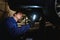 Close-up of a mechanic, technician, auto engineer checks the underbody of the car with flashlight in the garage of a repair shop.