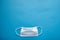 Close-up of medical mask on blue background with empty space, top view. Concept of mutual medical assistance and support