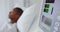 Close-up of medical monitor with African american male patient in the ward at hospital