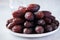 Close up of Medjoul dates in a white plate on a gray background
