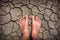 Close up of men feet on dry cracked earth texture for background, top view global warming concept