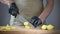 Close-up of men\'s hands in black disposable gloves. The cook in an apron s slicing potatoes on a cutting board.