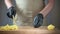 Close-up of men\'s hands in black disposable gloves. The cook is slicing potatoes on a cutting board. Background in blur.