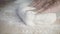 Close-up of men\'s hands kneading pizza dough at home on a light wooden table with white flour