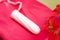 Close up of a a menstruation cotton tampon over a red cotton bag, with a beautiful red flower, in a blurred background