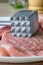 A close up of a metal meat tenderizer hammer utensil