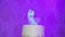 Close-up metal small statue of groom with bride in wedding dress with light reflection stands on top of cake