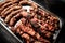 Close-up of metal tray with ready-made grilled pieces of beef meat.