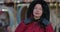 Close-up of middle-aged brunette Caucasian woman in red coat putting on hood. Beautiful positive lady standing on city