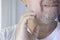 Close up of a middle-aged Latino man scratching his jaw. Barely grown beard. Gray beard