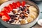 Close up of millet porridge with fruit, chocolate and nuts