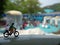 Close up Mini Figure Woman toys bicycling at Water Park White Horizontal Pool with negative or copy space for text area placement