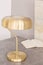 Close-up of a minimal stylish gold color desk lamp and an open book on a table in an office interior. Real photo.