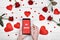 Close up of mobile smart phone with sign Be mine in woman hand, red paper hearts and rose flowers on wooden background, copy space