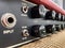 Close-up modern black volume knob of the boutique clean guitar amplifier with blurred black control panel and red leather cover.