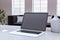 Close up of modern designer office workplace with empty mock up laptop screen and other items. Blurry office interior background.