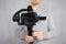 Close up of modern dslr camera on 3-axis gimbal stabilizer in male videographer hands over grey