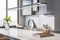 Close up of modern marble kitchen island with glass kettle, various objects, window with city view and daylight.
