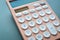 close up modern peach colour pastel calculator and white button on blue background, business and finance concept