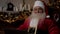 Close up modern Santa Claus uses laptop turns head looks into camera with smile