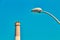 Close up on modern street lamp post and Reading power plant chimney in the background on a sunny day at Tel Aviv city