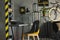 Close-up of a modern, yellow chair at a gray desk with a typewriter and black lamp in home office interior for a writer with dark