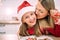 Close-up of mom and daughter in red sweaters in the kitchen and santa ha