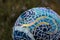 Close-up of mosaic garden ball in multicolored shades of blue made from stained glass tiles, abstract design dipicting the flow of