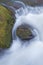 Close up of mossy rock with flowing water rushing downstream