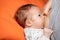 Close up mother breastfeeding her newborn child on a bed in a bright room.