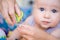 Close-up mother cutting nail of baby with safety scissors. Mom trimming child fingernails. Children healthcare and hygiene concept