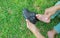 Close up mother hands putting small shoes to her son in the green lawn